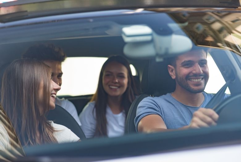 Quatro jovens dentro de um carro sorrindo